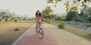 亚洲女孩在阳光明媚的日子里骑自行车，健康的生活理念。