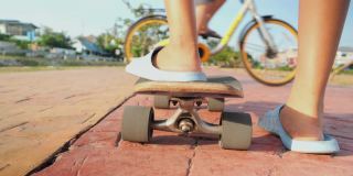 在阳光明媚的日子里，孩子的双腿在人行道上玩滑板，生活理念。