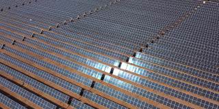 太阳能电池板的鸟瞰图与太阳反射在温暖的热沙漠。绿色能源、生态、清洁替代能源理念。可再生能源光伏电池场