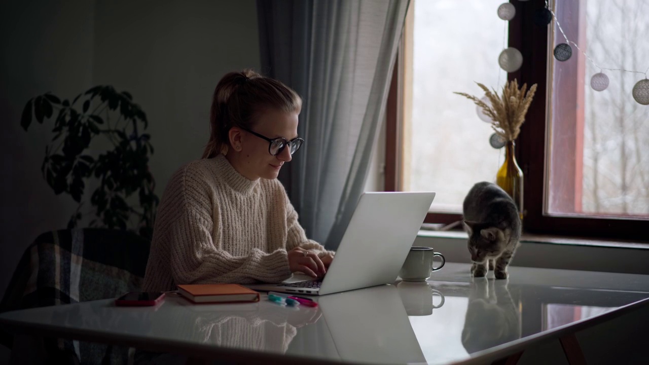 一个年轻女孩在家里工作或学习的时候在笔记本电脑上打字