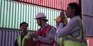 工程师和领班团队在安全帽和安全背心控制装载集装箱箱从货物，码头工人团队在船厂，物流概念。