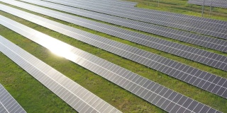 现场安装的一排排太阳能电池板。航拍可再生绿色能源的太阳能发电站。太阳能电池板表面的太阳反射。生产清洁生态能源。近距离