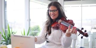 一位年轻的女音乐家，她在家拉小提琴，并在网上学习