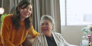 幸福亚洲家庭坦诚的女儿和儿子拥抱祖父母妈妈年长的妈妈舒适放松在沙发沙发惊喜访问在家里的客厅，一起拥抱快乐的亚洲家庭在家里