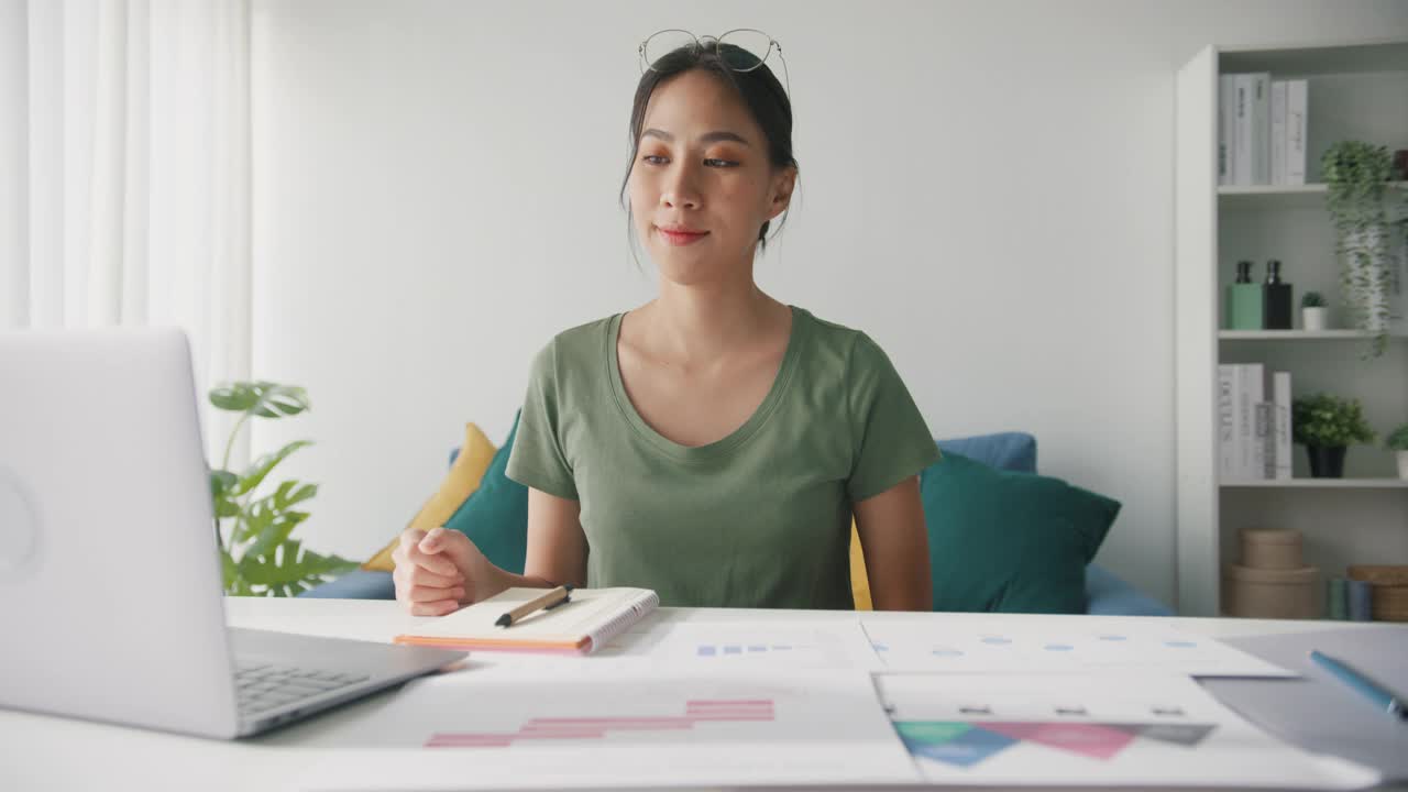 亚洲商业女性伸展身体放松，而工作的笔记本电脑在客厅在家里。