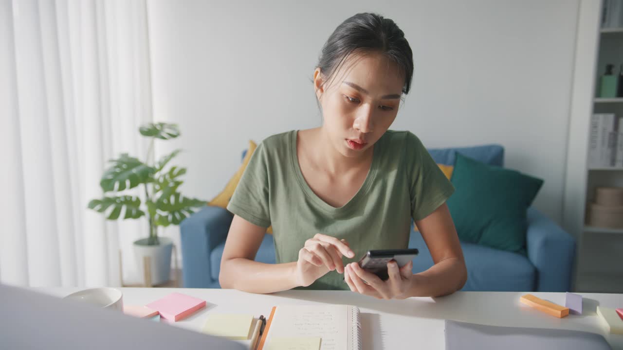 疲倦的年轻亚洲商业妇女在休闲使用电话在客厅在家里。