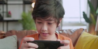 亚洲男孩沉迷于手机游戏，沉迷于手机游戏，退出亚洲男孩手玩智能手机游戏，躺在家里客厅的地板上，呆在家里的想法概念