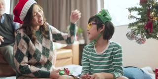 亚洲妈妈和她的孩子与圣诞服装装饰圣诞树与玩具和球。概念幸福的家庭准备新年，以及圣诞节和节日的心情。