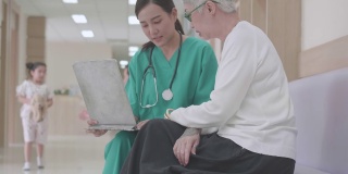 医生仔细地向老年患者讲解充电器上的医学检查结果。年轻的亚洲女护士护理人员支持与老年妇女病人交谈，帮助解决问题。医院的概念，保健。