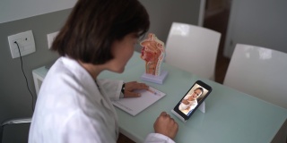 医生在一个远程医疗视频电话与老年患者使用移动电话在医疗诊所