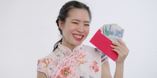 中国/亚洲妇女穿着旗袍，白色花卉图案的衣服，手里拿着红包送给她的家人、亲戚、后代和追随者，表示新年快乐、富裕、幸福和幸运
