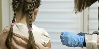 正在给学龄女孩接种疫苗。强制性的疫苗接种。这孩子在诊所里肩部注射了疫苗