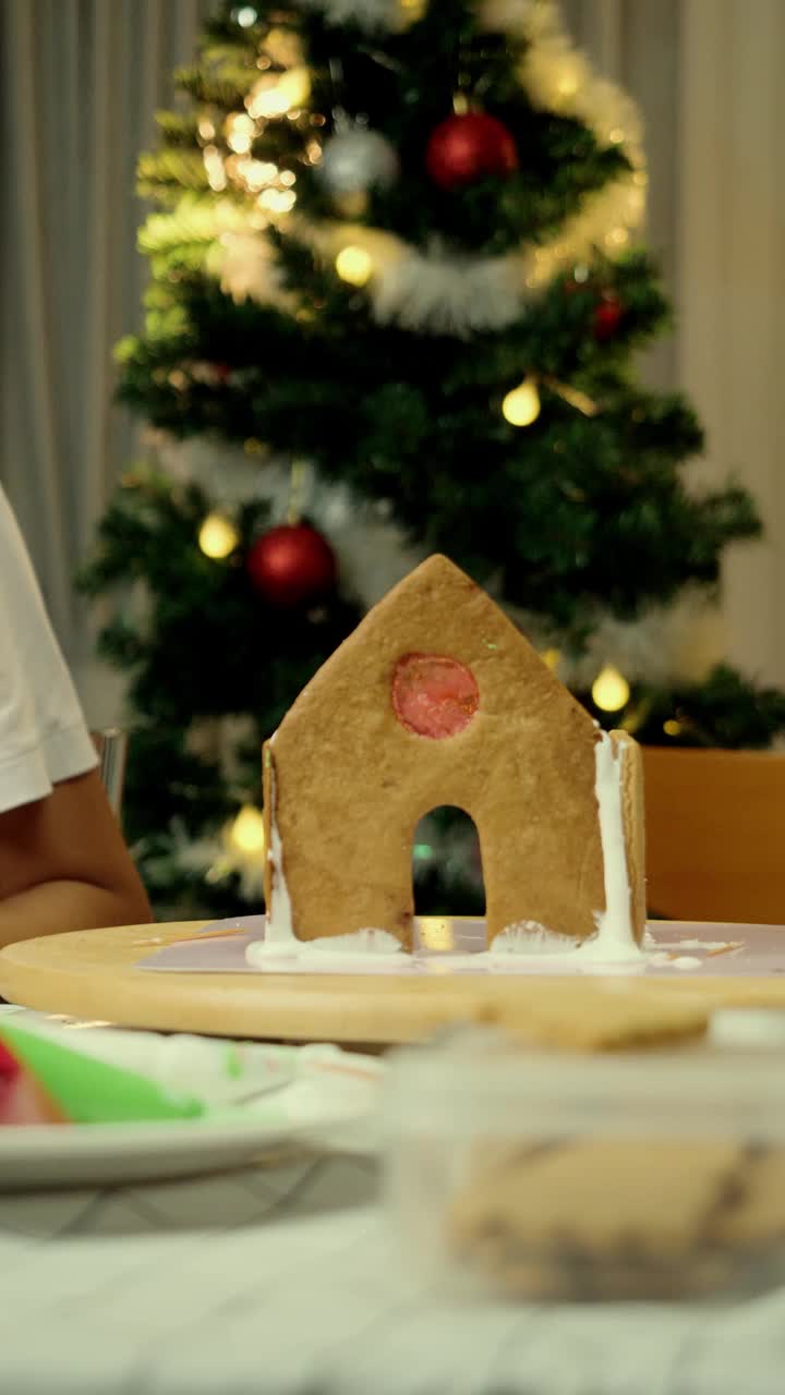 亚洲女孩在晚上在家做姜饼屋，庆祝圣诞节的生活方式概念。
