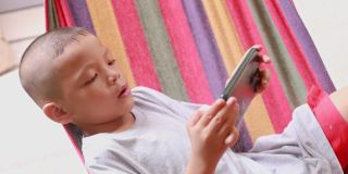 孩子躺在婴儿床上玩手机