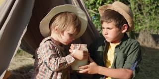 野餐在大自然中，开朗饥饿的孩子们喜欢在户外帐篷野餐时吃面包喝牛奶