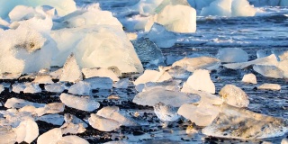 黑色沙滩上的大块冰，全球变暖，气候变化的概念，冰岛钻石海滩Jokulsarlon冰川泻湖的冰山
