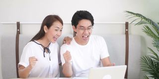 慢动作激动的亚洲夫妇使用笔记本电脑，获奖者
