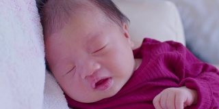 可爱的睡着的新生儿放松在妈妈的手臂安全舒适。微笑亚洲新生儿宝宝休息睡觉香甜的梦。母亲抱着婴儿。新生儿摄影概念