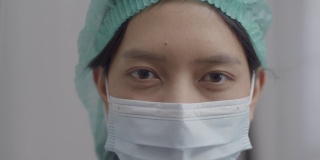 在COVID-19大流行期间，亚洲护士戴着口罩，穿着医疗防护服在医院工作。