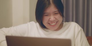 亚洲妇女看着笔记本电脑，笑得很开心