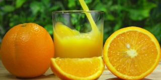 新鲜甜橙汁倒在一个玻璃杯里，旁边是成熟的大桔子