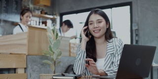 美丽的亚洲女人在咖啡馆用智能手机写信息。