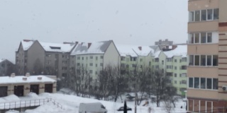 下雪了。模糊的背景，在住宅建筑的背景下飘落的大片雪花。丰富的雪花。从公寓看到的景色