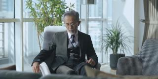 成功的亚洲华人CEO商人坐在办公室休息室看着别处