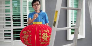 亚洲华人男子挂红灯笼在他家的前院在中国新年前夕