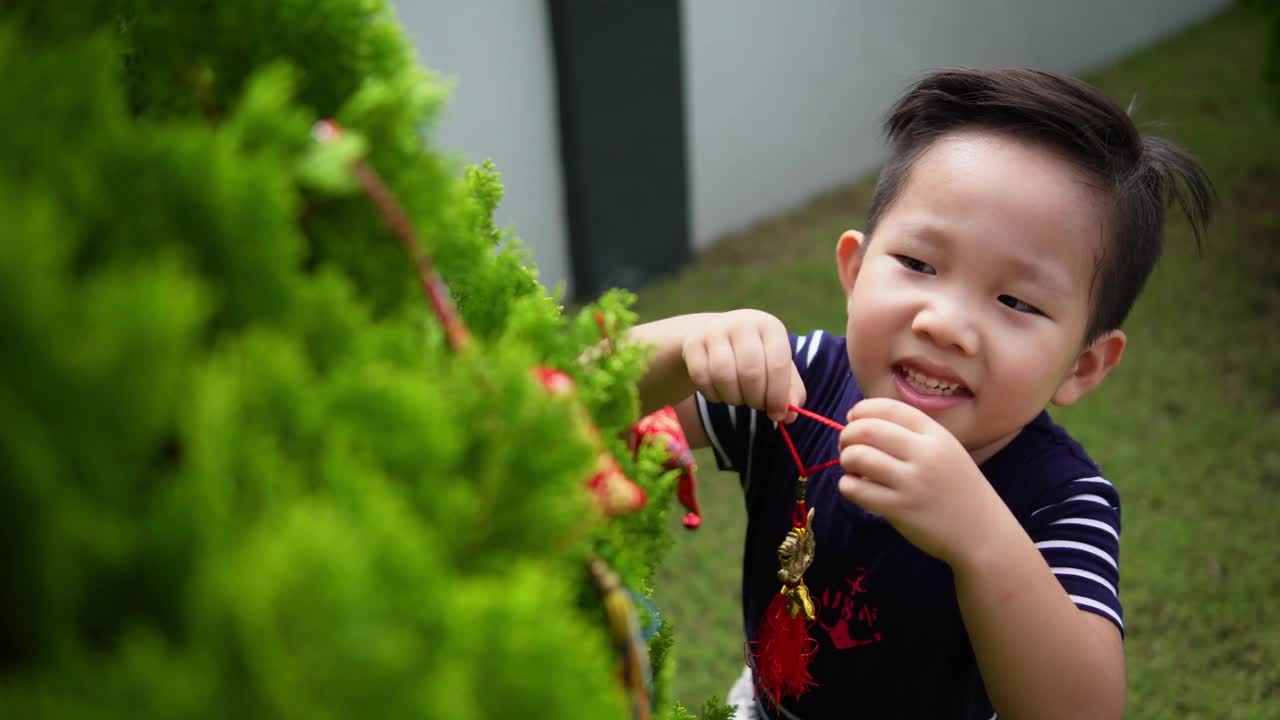 亚洲华人微笑的小男孩在树上装饰中国新年的装饰品