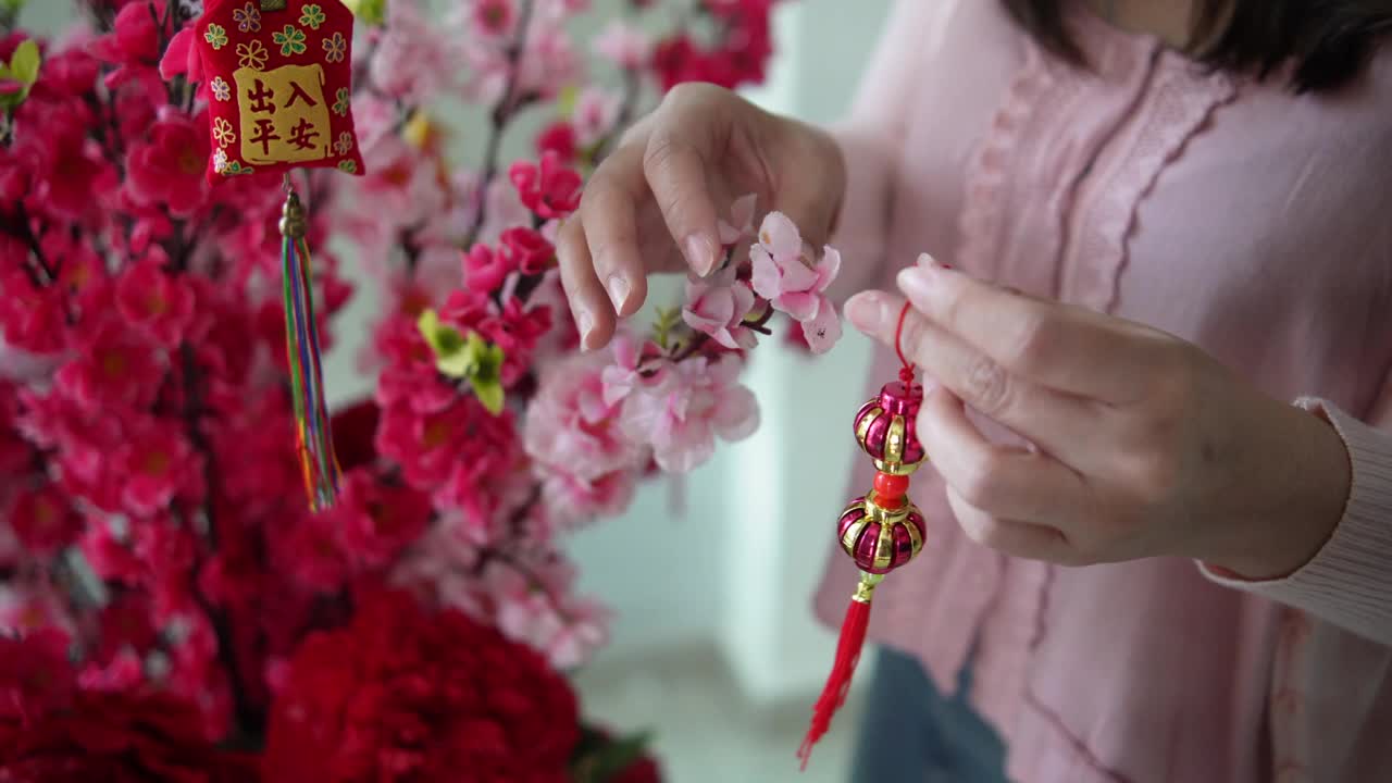 亚洲华人微笑的妇女在樱花上装饰中国新年的装饰品