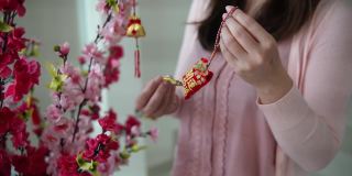 亚洲华人微笑的妇女在樱花上装饰中国新年的装饰品