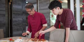 在中国新年期间，亚洲的中国年轻人和他的父亲在餐桌上准备食物