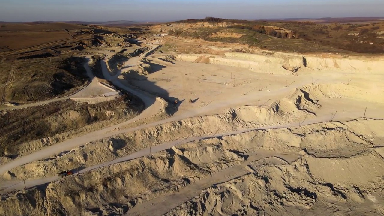 露天矿山建筑用砂石材料用挖掘机和自卸卡车的鸟瞰图。重型设备在采矿和生产中具有实用的矿物概念