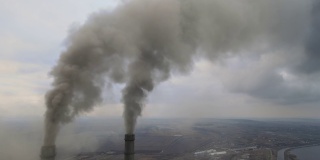 从空中俯瞰燃煤电厂高高的管道，黑烟在污染的大气中向上移动