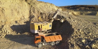露天矿山建筑用砂石材料用挖掘机装石料自卸卡车鸟瞰图。重型设备在采矿和生产中具有实用的矿物概念