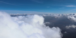 从飞机窗口俯瞰，高空的地面上覆盖着白色蓬松的积云