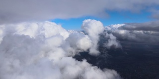 从飞机窗口俯瞰，高空的地面上覆盖着白色蓬松的积云