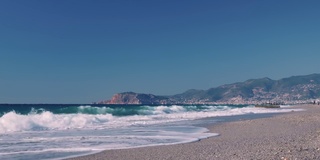 阳光明媚的夏日，热带海滩。海浪拍打着沙滩，形成白色的泡沫状纹理。美丽的海岸线和海滨