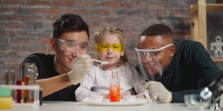 化学家将催化剂倒入女孩和老师看着反应