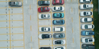 从空中俯瞰，停车场里停满了不同颜色的汽车。相机向前移动