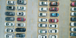 从空中俯瞰，停车场里停满了不同颜色的汽车。相机向前移动
