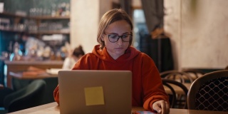 年轻的白人女性自由职业者或博客作者在咖啡馆用笔记本电脑工作。大学生使用科技，在线教育，自由职业。