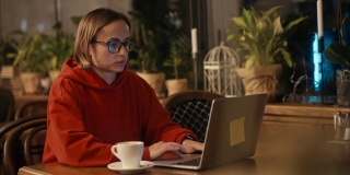 年轻的白人女性自由职业者或博客作者在咖啡馆用笔记本电脑工作。大学生使用科技，在线教育，自由职业。