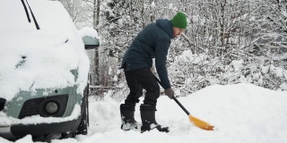大雪过后，一名男子正在铲雪车附近的道路。冬天天气恶劣，自然灾害严重。由于暴风雪，清理后院区域的人员。
