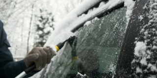 特写人物用碎片从车窗移开冰雪和冻霜。冬天天气冷，自然灾害大。一名男子在暴风雪后清理他的汽车。缓慢的运动。