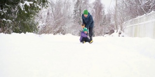 风雪过后，父亲和儿子在乡村道路上铲雪，享受冬天的乐趣。爸爸骑着他的孩子用铲子。