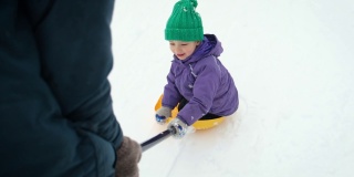 在暴风雪中，波夫的父亲骑着他的小孩在乡村公路上铲雪。冬天，爸爸和儿子在后院铲雪。