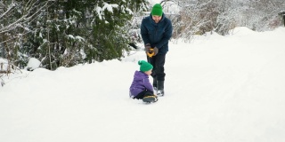 爸爸骑着他的孩子在铁铲上慢动作。风雪过后，父亲和儿子在乡村道路上铲雪，享受冬天的乐趣。