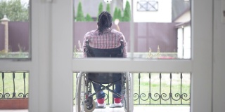 后视镜瘫痪的非洲裔美国人父亲坐在轮椅上，欣赏着愉快的十几岁的模糊的女儿踢足球的慢镜头。快乐的残疾人享受周末与女孩在户外。